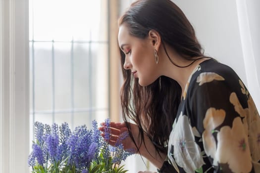 Side view portrait of attractive dark haired girl bending over purple flowers Horizontally.