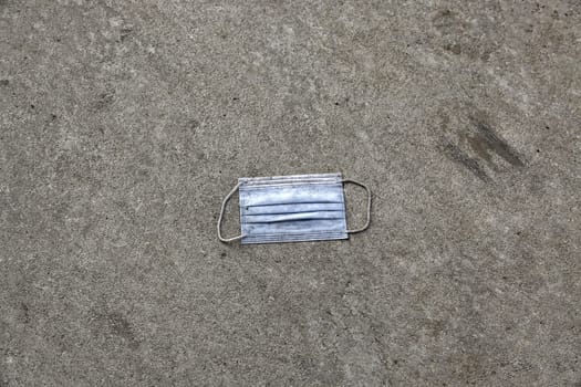Detail of mask for covid thrown in the street, dirt