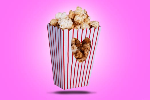 Popcorn in a box with a love heart cutout. Red striped packaging with snack food and a pink background.