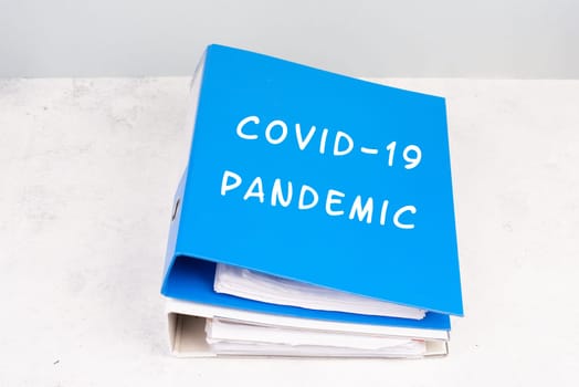 The words Covid-19 pandemic are standing on a folder, outbreak of virus infectious disease, processing of the regualtions, documents for evidence