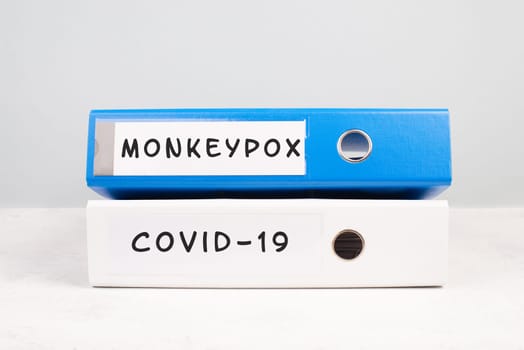 The words monkeypox and Covid-19 are standing on a folder, outbreak of virus infectious disease, processing of the pandemic, documents for evidence