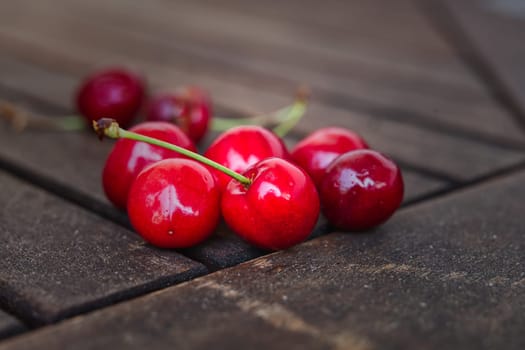 a bunge of cherries lying on wooden ground