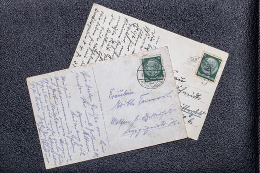 Potsdam, Germany - MAY 06, 2022. Old postcards from 1935 and 1939 with stamps showing the portrait of the German Reich President Paul von Hindenburg, Germany, Third Reich. Black background.