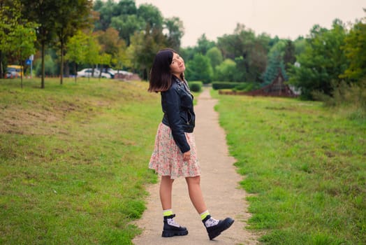 Smiling young girl pulled her straight leg to the heel while standing on a path in a green park