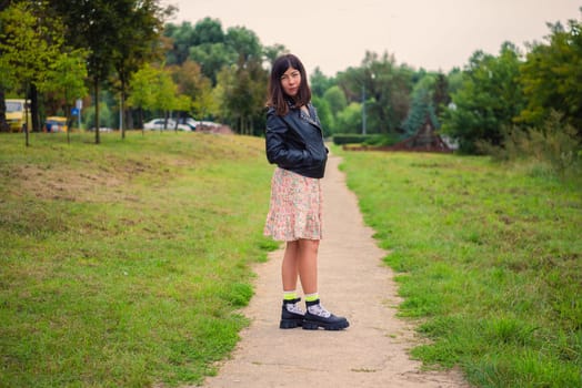 a woman with black long hair walks in a green park