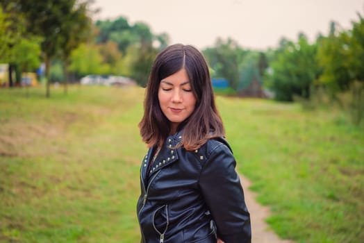 portrait of a smiling young girl with closed eyes in a black jacket