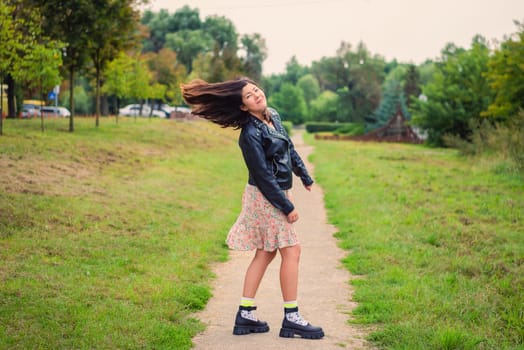 beautiful young smiling woman twists her head with long black hair in nature