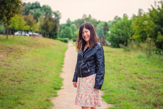 smiling young woman standing on the path in the park