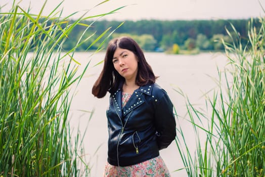 portrait of a young woman in a black jacket on the shore of a large lake