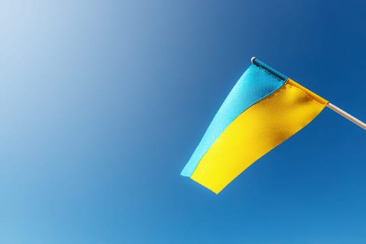 Large bicolor yellow blue Ukrainian state flag, national symbol fluttering, waving in wind against blue sky on sunny day. Kyiv city, capital of Ukraine, Independence Constitution Day, National holiday