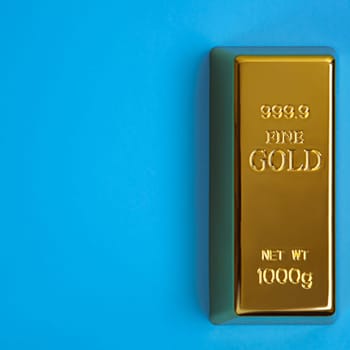An ingot of gold metal bullion of pure brilliant diagonally located on a blue background