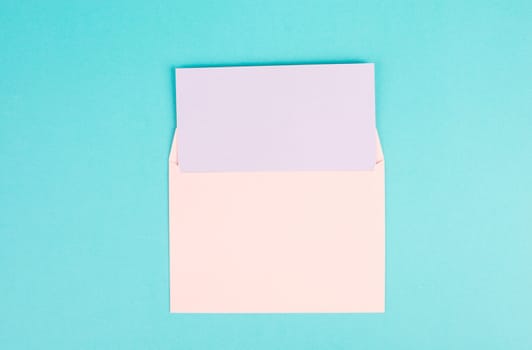 Pink colored envelope with an empty with paper on a turquoise background, copy space for text, greeting card, communication and announcement concept, reminder