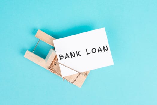 Paper with the words bank loan in a mousetrap, finanicial debt, inflation, risky credit and investment