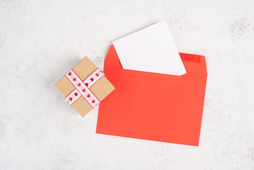 Red envelope with an empty paper, gift box with hearts, textured background, birthday, mothers day, fathers day and valintines day greeting card