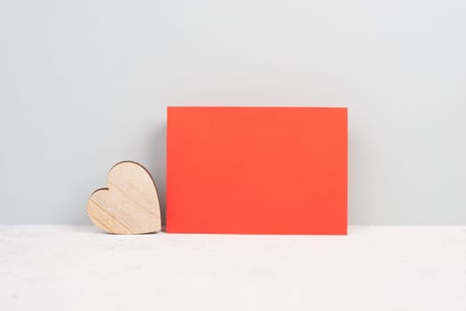 Red envelope with an empty paper, wooden heart, textured background, birthday, mothers day, fathers day and valintines day greeting card
