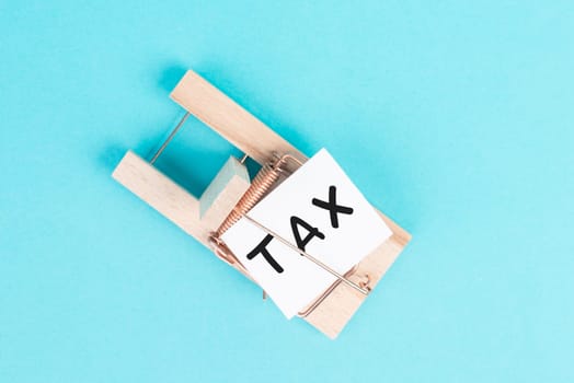 Paper with the word tax in a mousetrap, high financial burden, costs and expenses in business, taxation by the state
