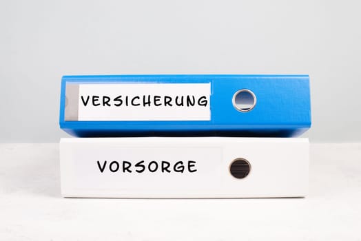 Two folders with the words insurance and precaution in german langauge, documents at an office, risk protection, financially security