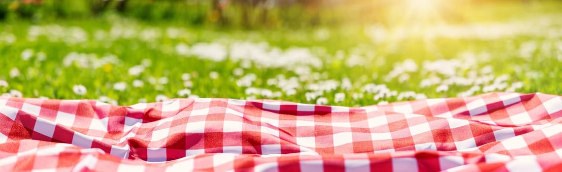 Closeup view of the picnic duvet on the meadow with green grass and spring flowers. Concept of tourism and leisure.