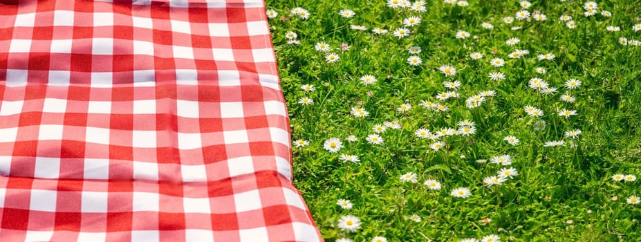 Picnic duvet on the meadow with green grass and spring flowers. Concept of tourism and leisure.