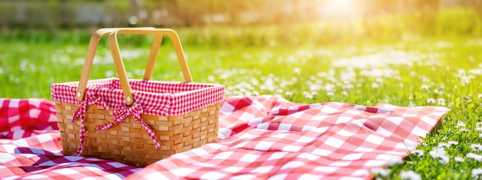 Picnic duvet with empty bascket on the meadow in nature. Panoramic view. Concept of leisure and family weekend.