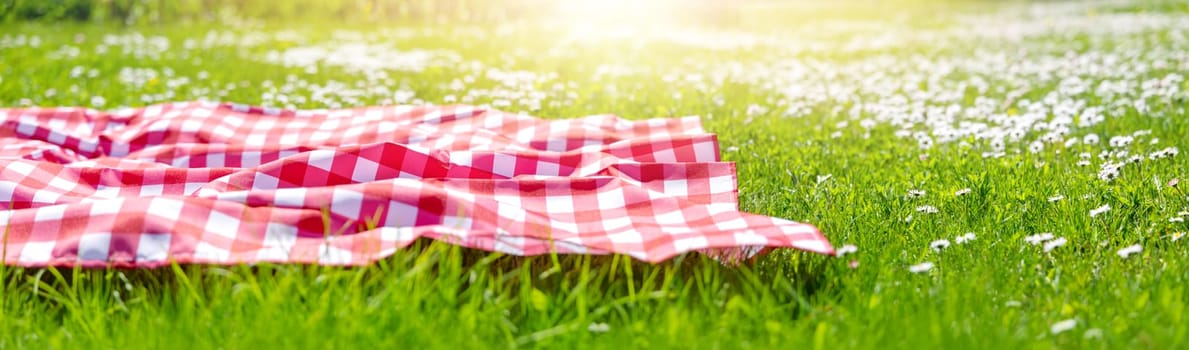 Picnic duvet on the meadow with green grass and spring flowers. Concept of tourism and leisure.