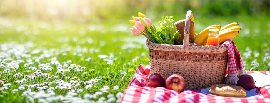 Picnic bascket on the duvet on the meadow in the nature. Concept of leisure, romantic dinner and family weekend.