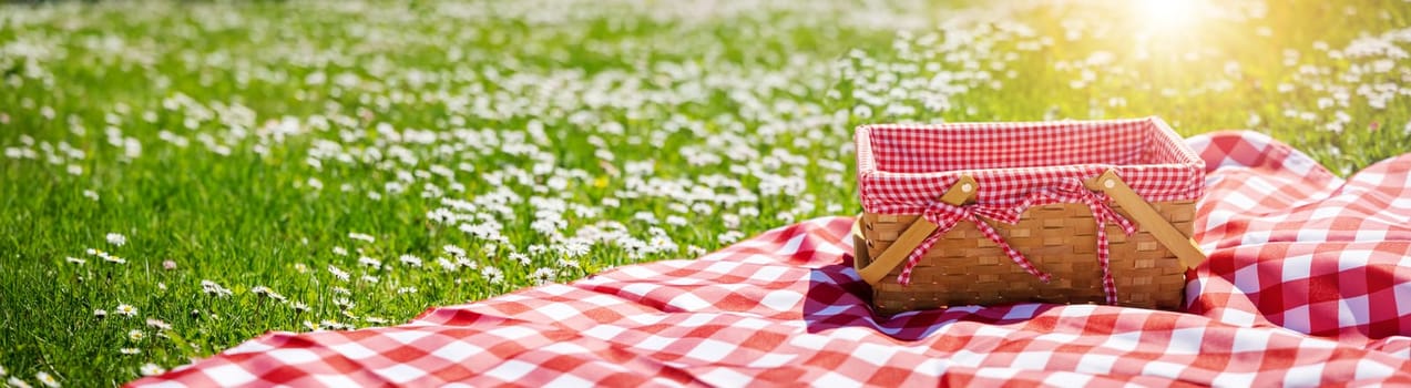 Picnic duvet with empty bascket on the meadow in nature. Panoramic view. Concept of leisure and family weekend.