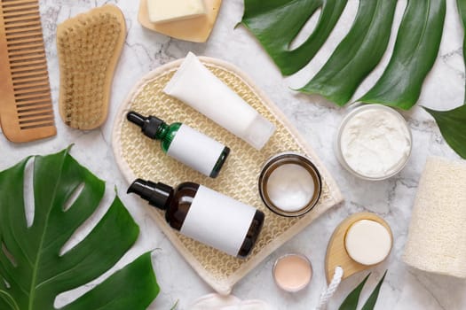Homemade organic cosmetics and eco friendly accessories near monstera leaves flat lay, copy space. Brand packaging mockup. Natural beauty products for hair and skin care, Top view