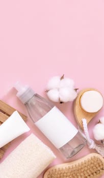 Homemade organic cosmetics in tubes and bottles and eco friendly accessories on pink flat lay, copy space. Top view of natural beauty products for hair and skin care