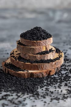 Indian spice Black cumin (nigella sativa or kalonji) seeds on grey table with a wooden spoon, close up with copy space. Traditional asian medicine, healthy and vegetarian food concept