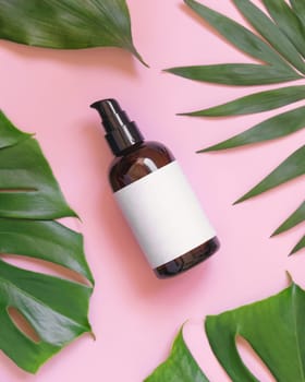 Brown one pump Bottle between tropical leaves on pink top view. Brand packaging mockup. Natural herbal cosmetics concept - Aromatic oil, skincare beauty product, cream or serum..