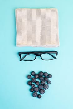 Human face made with a wool hat, glasses and blueberries as a beard, funny minimalist portrait, eco freak lifestyle, vegan food