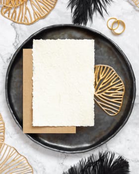 Black and golden wedding table setting with a blank card top view, mockup. Elegant flat lay with vertical greeting or Invitation paper card, wedding or holiday stationery template