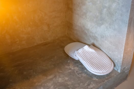 Slippers placed beside the concrete wall house