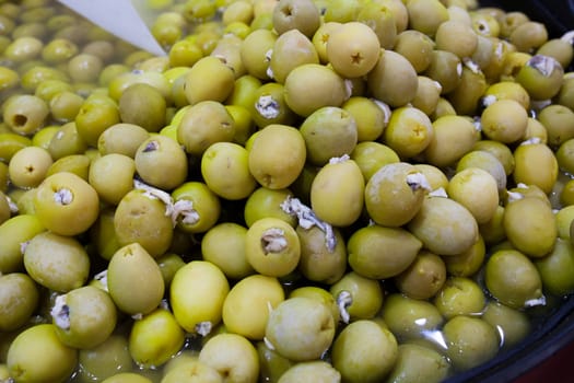 Pickled olives stuffed with vinegar pickled anchovies. Delicious pickled snack displayed plastic basket