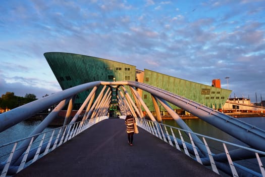 AMSTERDAM, NETHERLANDS - MAY 9, 2017: NEMO Science museum and Mr. J.J. van der Veldebrug bridge. It is the largest science center in Netherlands with over 500000 visitors per year