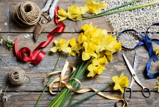 Bouquet of narcissus and gardening tools on rustic wooden table