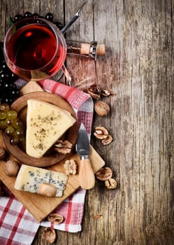 Glass of red wine and cheese on rustic wooden background