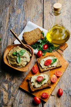 Mediterranean cuisine recipe. Hummus and baba ganush with homemade bread slices and cherytomatos on wooden table.