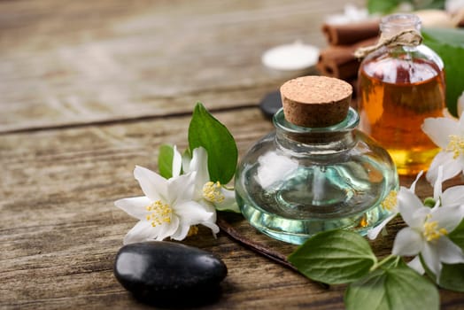 Essential oils with jasmine, cinnamon and vanilla on rustic wooden table
