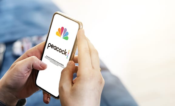 New York, USA, September 2021: woman launching the Peacock Tv mobile app on her smart phone. Peacock is an American video streaming service