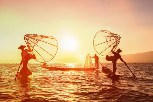 Myanmar travel attraction landmark - three traditional Burmese fishermen at Inle lake, Myanmar famous for their distinctive one legged rowing style