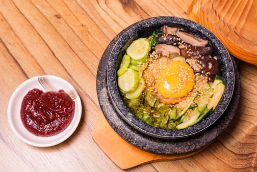 Bibimbap in a black heated stone bowl, Korean traditional dish- bibimbap mixed rice with vegetables Include beef and fried egg, Japanese hot pot food