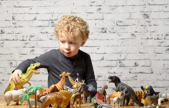 a little child plays with toys animals and dinosaur