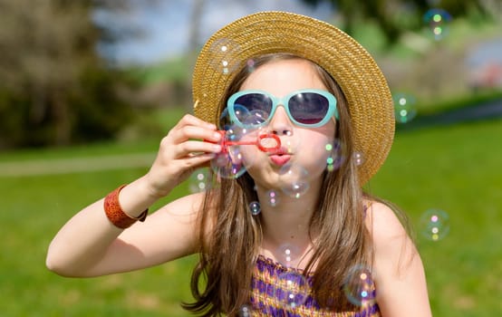 a little girl making soap bubbles in nature