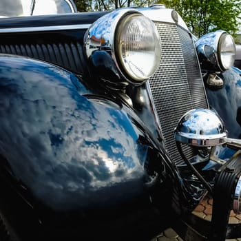 Old retro or vintage car or automobile front side with front lights or headlights and radiator grill