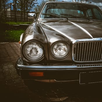 Old retro or vintage car or automobile front side with front lights or headlights and radiator grill. Processed by vintage or retro effect filter
