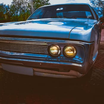 Old retro or vintage car or automobile front side with front lights or headlights and radiator grill. Processed by vintage or retro effect filter