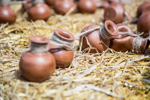 Small ceramic crocks or pot countryside decoration or souvenir on straw. Selective focus of image on one of crock