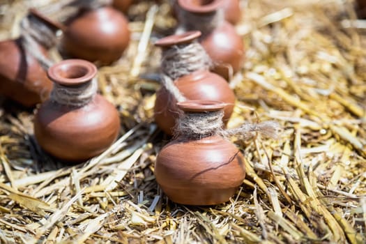 Small ceramic crocks or pot countryside decoration or souvenir on straw. Selective focus of image on one of crock